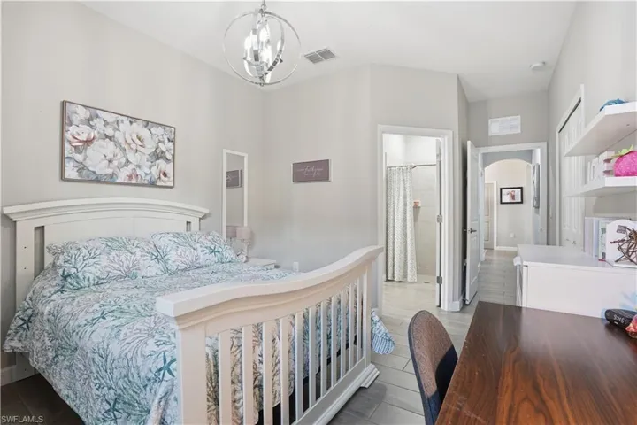 Bedroom featuring suspended lighting, arched walkways, and ensuite bath