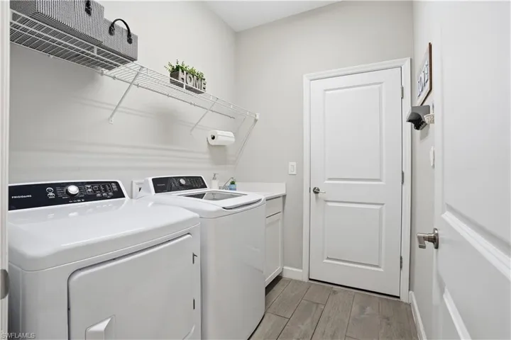 Laundry room with light wood finished floors, washer and clothes dryer, and cabinet space