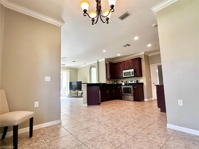 Kitchen featuring ornamental molding, dark countertops, a peninsula, stainless steel appliances, and hanging light fixtures