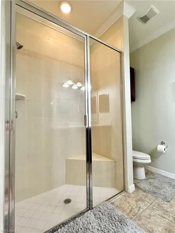 Bathroom with crown molding and a shower stall