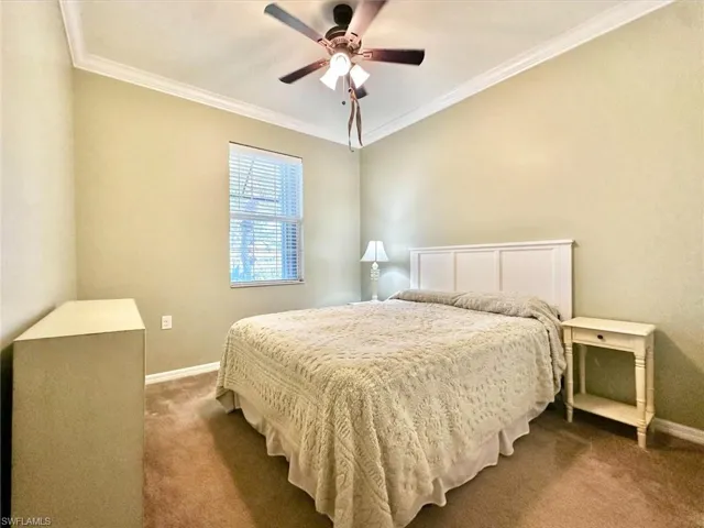 Carpeted bedroom with ornamental molding and a ceiling fan