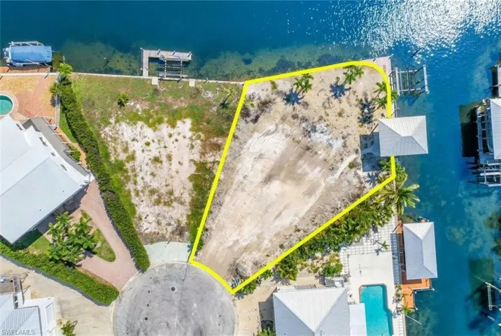 Waterfront parcel featuring a cul-de-sac entrance, mature palm trees, and direct water access - Virtually Edited Image