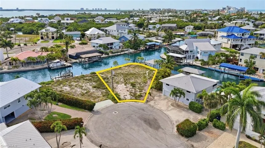 Waterfront lot featuring direct canal access, a cul-de-sac location, and surrounding mature tropical landscaping - Virtually Edited Image