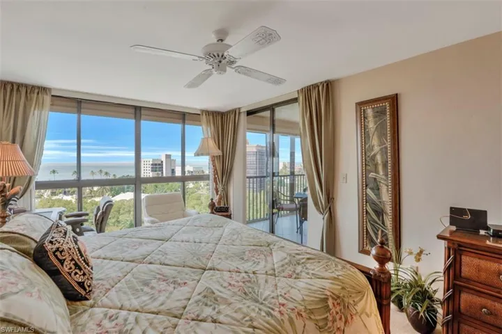 Bedroom with access to exterior, floor to ceiling windows, ceiling fan, and a water view
