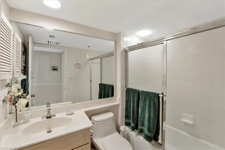 Full bathroom featuring enclosed tub / shower combo, vanity, and toilet