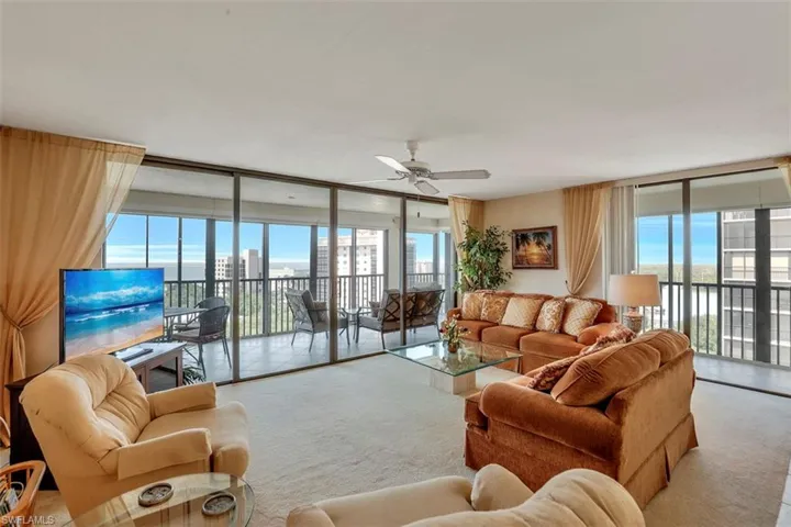 Living room featuring light carpet, plenty of natural light, and floor to ceiling windows