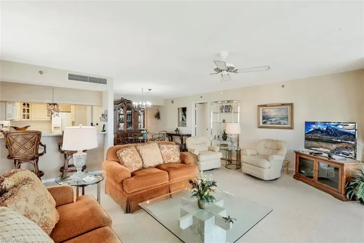 Carpeted living room featuring ceiling fan with notable chandelier