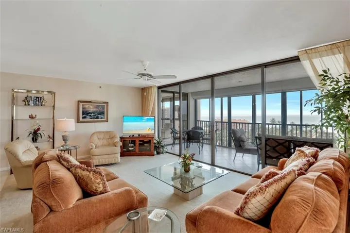 Living room featuring ceiling fan and a wall of windows