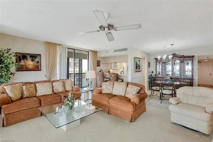 Living room with light colored carpet and ceiling fan with notable chandelier