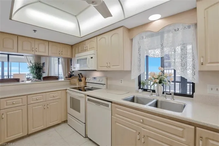 Kitchen featuring light tile patterned flooring, white appliances, sink, and a wealth of natural light