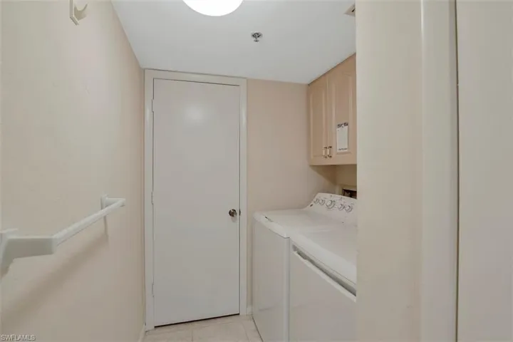 Washroom featuring cabinets, washer and dryer, and light tile patterned floors