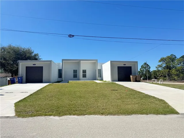 Contemporary home featuring stucco siding, a front lawn, and driveway