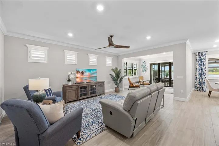 open concept great room featuring light tile flooring, a wealth of natural light, and crown molding