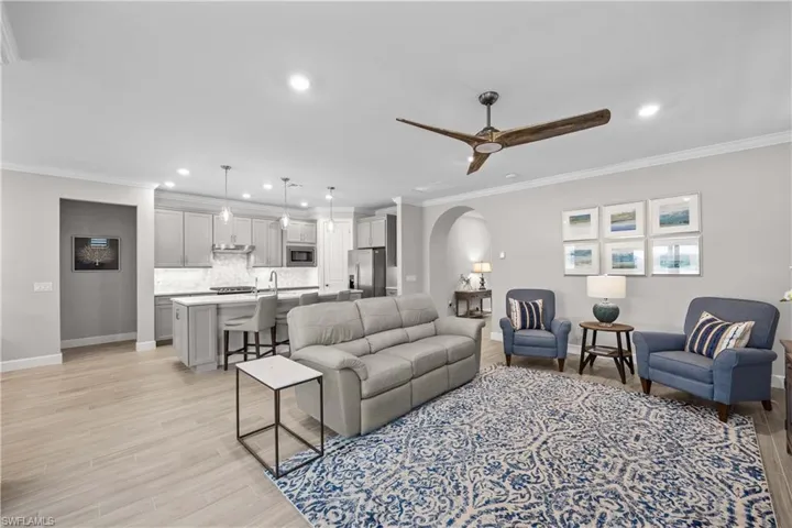 Open floor plan flows from great room into kitchen featuring modern ceiling fan, crown molding