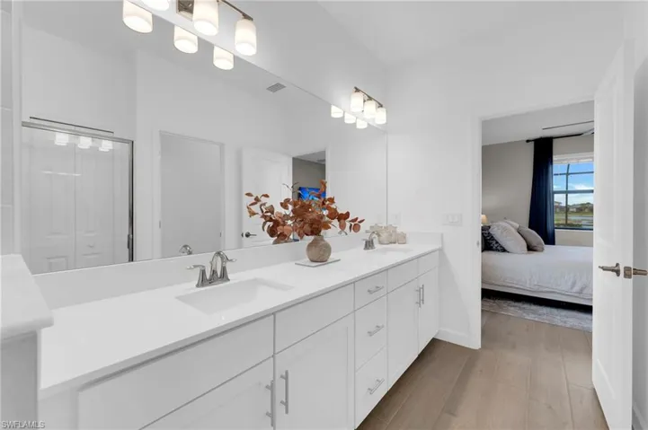 Ensuite bathroom with double vanity and light wood-type flooring