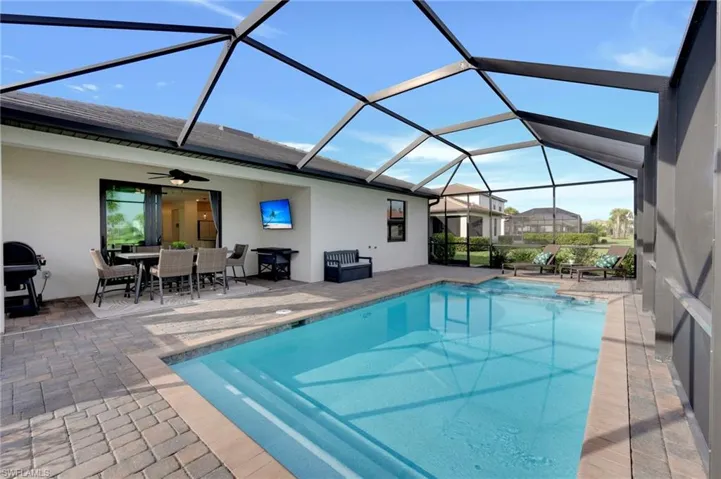 Outdoor pool with glass enclosure, a sunroom, a patio area, and outdoor dining area