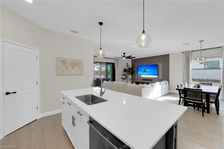 Kitchen featuring hanging light fixtures, ceiling fan, dishwasher, an island with sink, and open floor plan