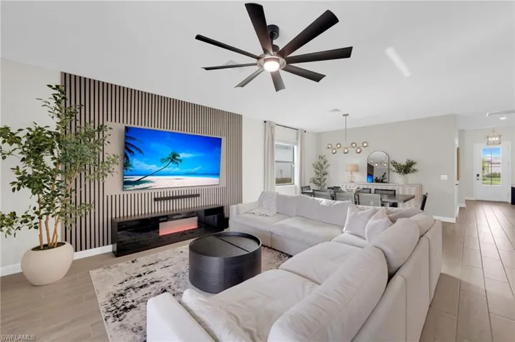 Living area with a chandelier, a ceiling fan, a glass covered fireplace, and wood tiled floors