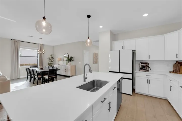 Kitchen with white cabinets, freestanding refrigerator, pendant lighting, backsplash, and recessed lighting