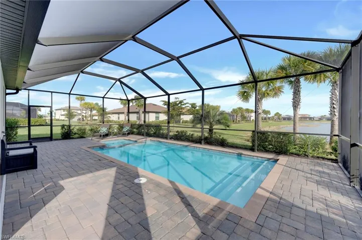 View of pool featuring a sunroom, a lanai, a patio area, a pool with connected hot tub, and a residential view