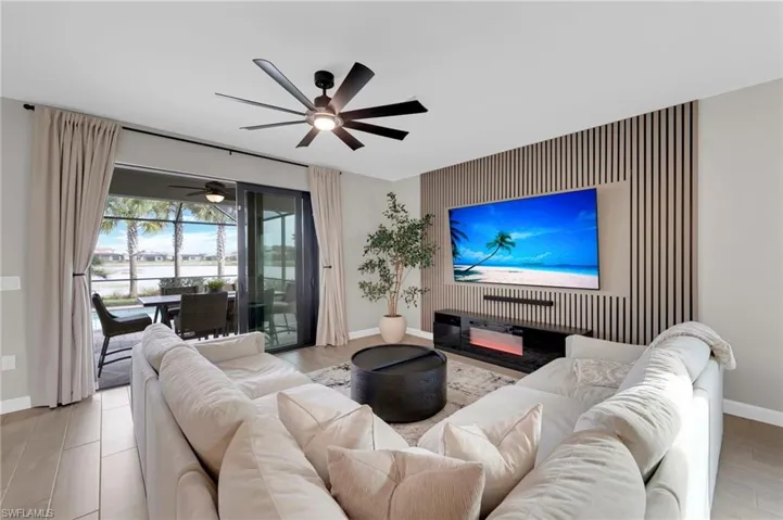 Living area featuring an accent wall and ceiling fan