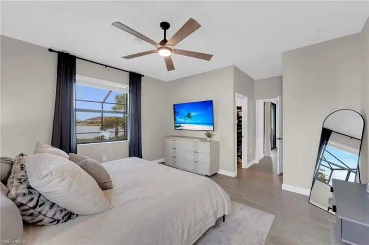 Bedroom featuring wood finish floors, a walk in closet, and ceiling fan