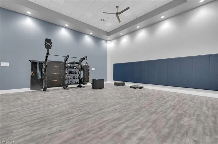 Workout area featuring ceiling fan, a towering ceiling, recessed lighting, and a paneled ceiling