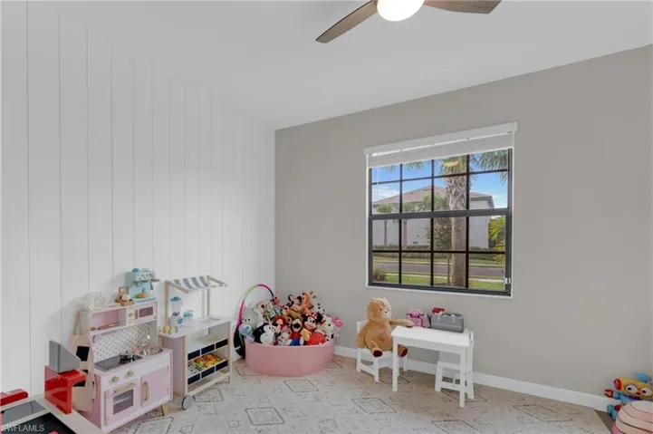 Recreation room with a ceiling fan and wood walls