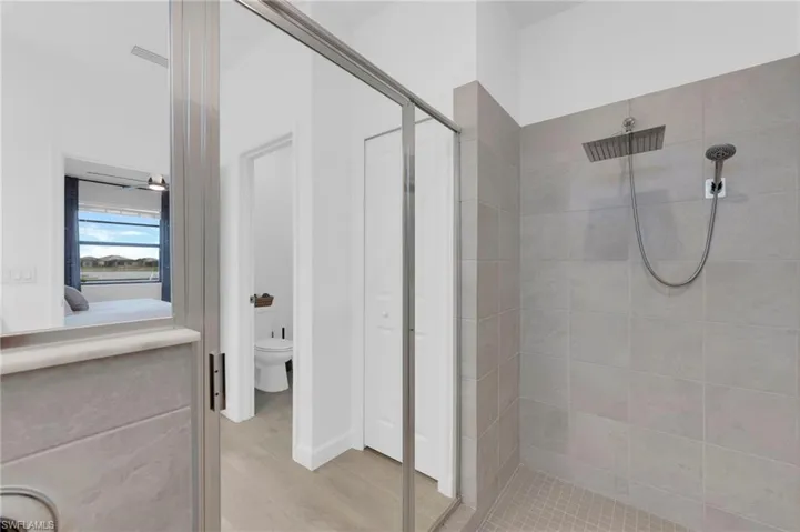 Full bath with a shower stall, ensuite bathroom, light wood-style floors, and a closet
