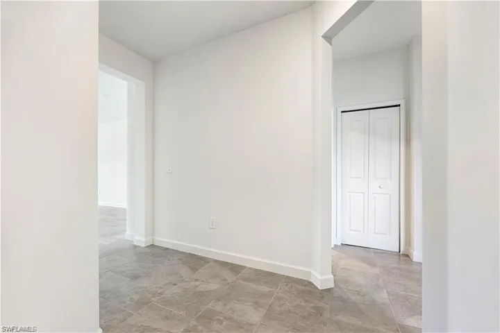 Neutral wall finishes, tiled flooring, white trim, and a white bi-fold door