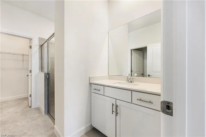 White vanity with integrated sink, chrome faucet, and expansive mirror