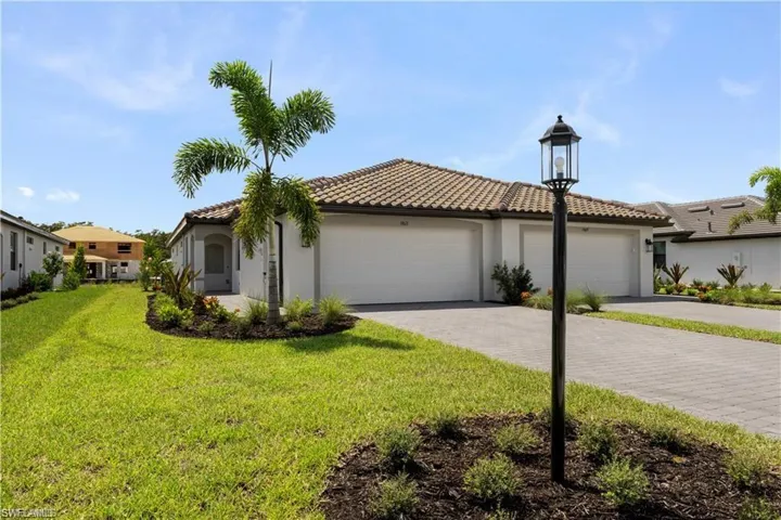 Single-story residence featuring a tile roof, dual garage doors, a paver driveway, and a decorative landscape light