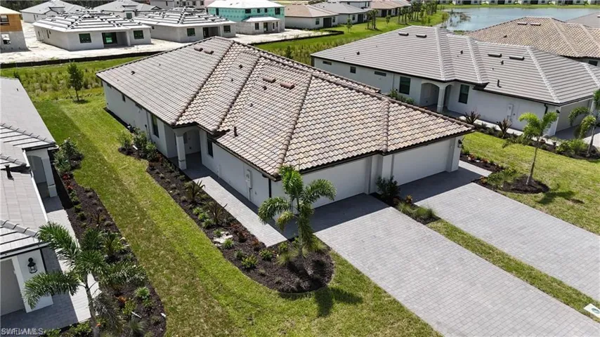 Tile roof, paver driveway, attached two-car garage, mature landscaping, and covered entry
