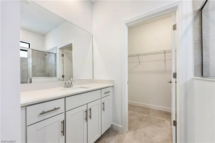 Vanity with white shaker cabinetry, an undermount sink, and a large wall-mounted mirror