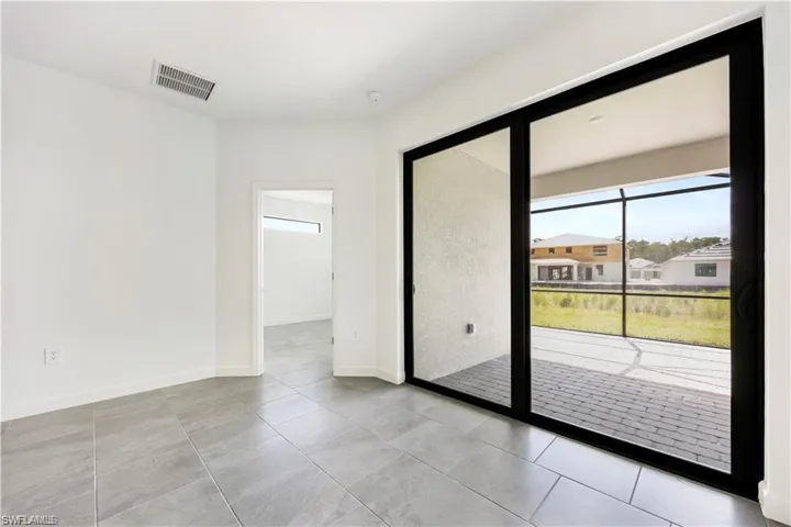 Sliding glass doors with black frames open to a screened lanai with paver flooring