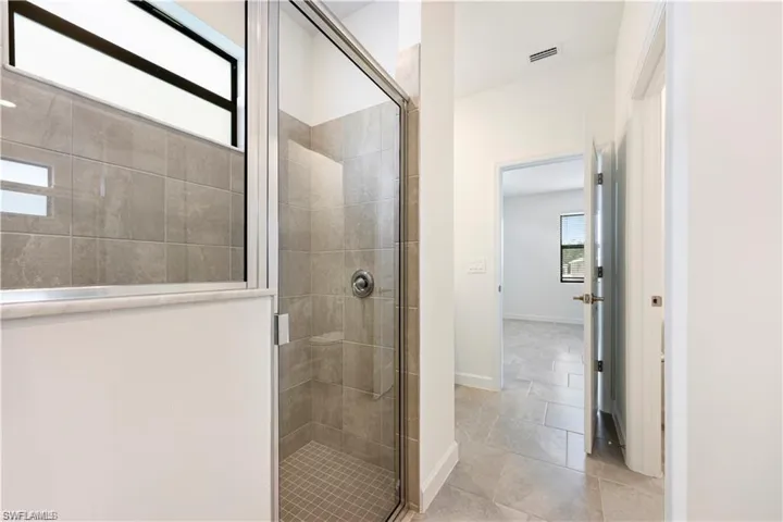 Glass-enclosed shower with full-height tile surround and a tiled shower pan