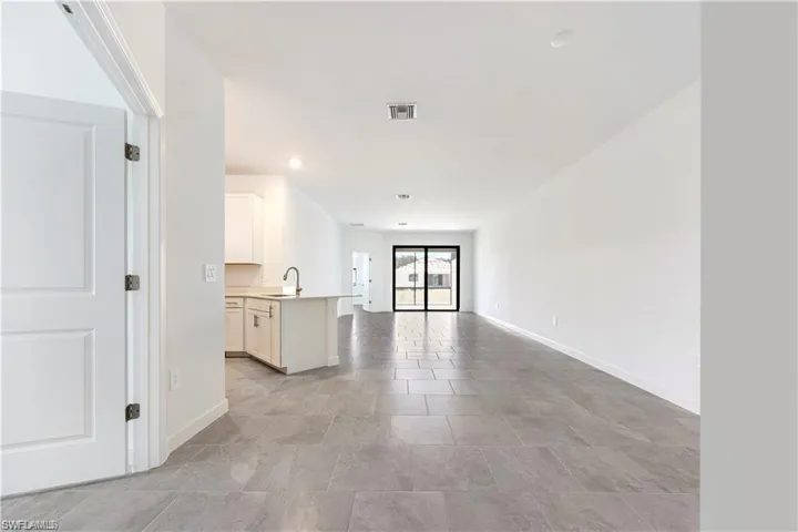 Open-concept interior featuring light gray tile flooring, white walls, and recessed lighting