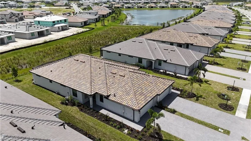 Tile roof, paver driveway, single-story residence, exterior landscaping, adjacent water feature