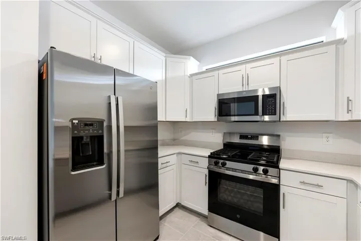 Kitchen featuring stainless steel appliances, white cabinetry, a gas range, and light-toned countertops