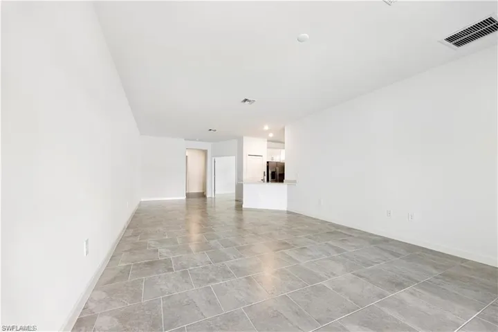 Expansive room featuring light-toned walls and large format tile flooring