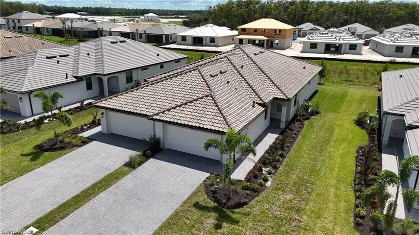 Contemporary single-story residence featuring a tile roof, stucco exterior, and an expansive paver driveway