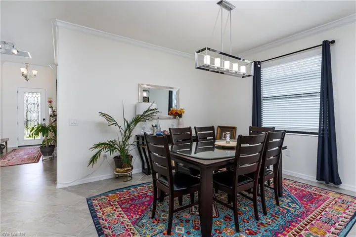 Tiled dining area with a wealth of natural light, crown molding, and a chandelier