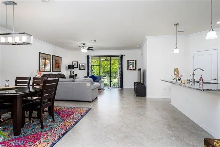 Tiled living room with ceiling fan, sink, and crown molding