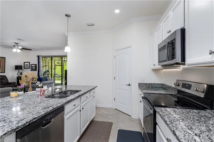 Kitchen featuring sink, white cabinets, appliances with stainless steel finishes, and light tile patterned floors