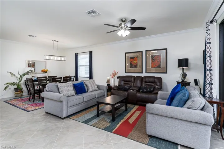 Tiled living room with ceiling fan and ornamental molding