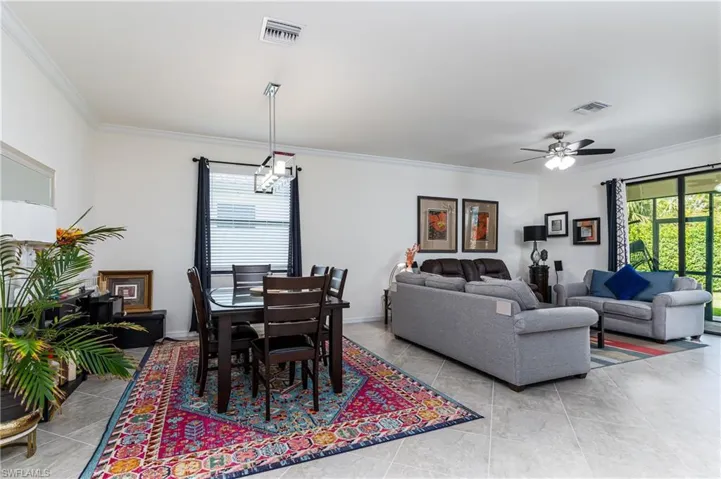 Dining area featuring ceiling fan, light tile patterned flooring, and crown molding