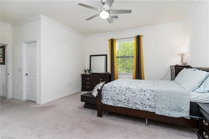 Bedroom featuring ceiling fan, ornamental molding, and light colored carpet