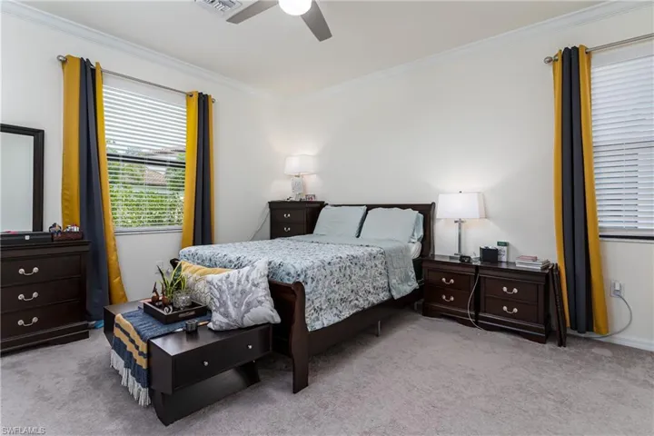 Bedroom with light colored carpet, crown molding, and ceiling fan