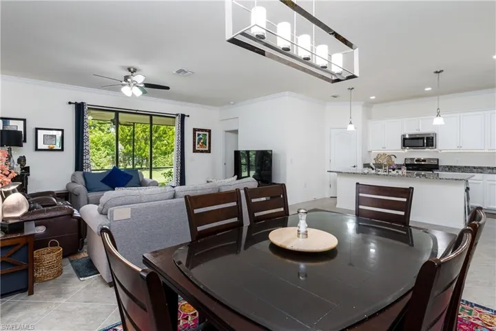 Dining room featuring crown molding, ceiling fan with notable chandelier, and light tile patterned flooring