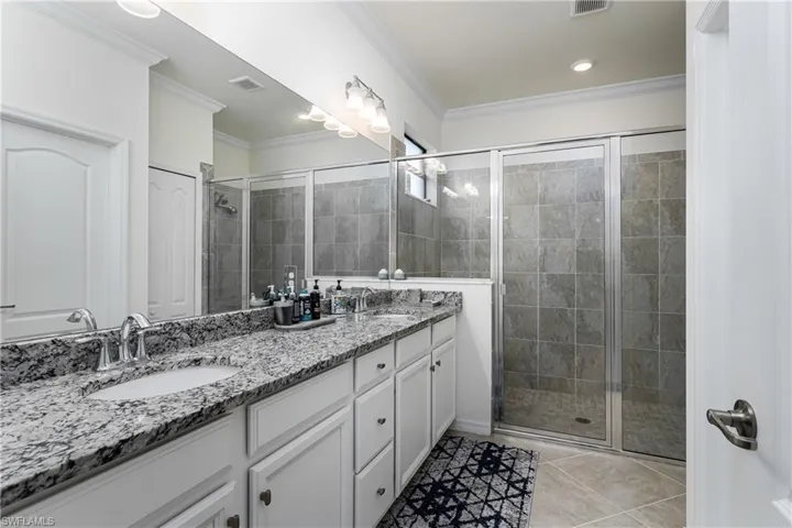Bathroom featuring a shower with door, ornamental molding, vanity, and tile patterned floors